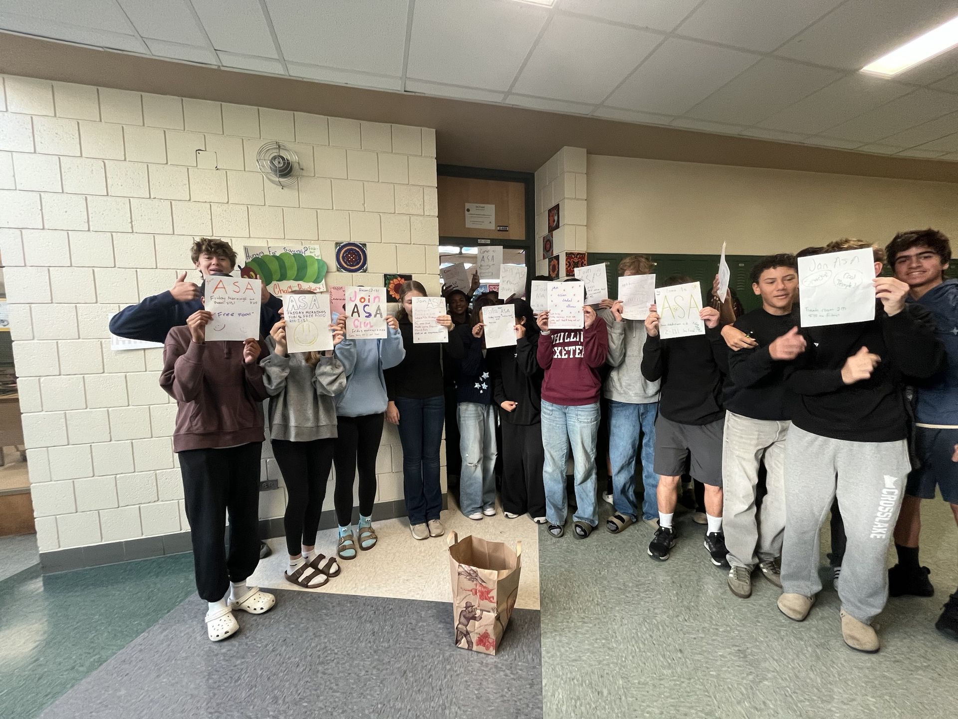 Mayo ASA members holding up hand-drawn ASA posters in a school hallway