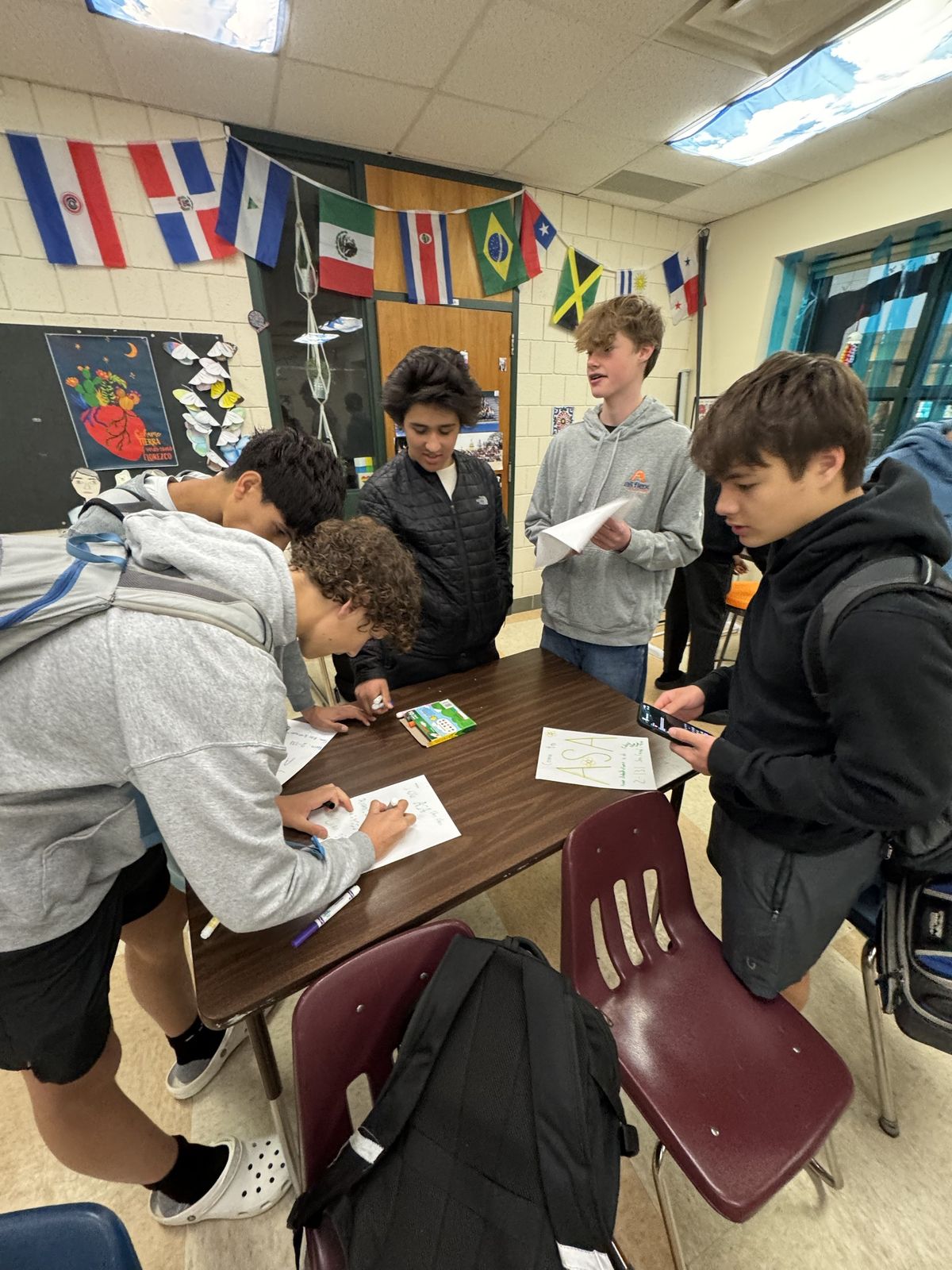 Students gathered around a table drawing ASA posters with markers